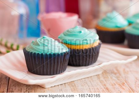 Two vanilla cupcakes with mint cream on a decorative plate