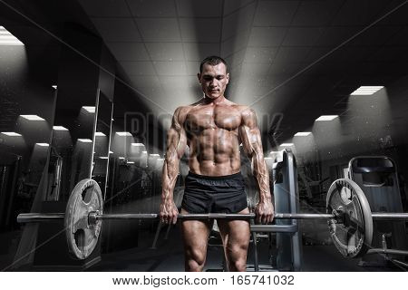 Muscular man workout with barbell at gym. Deadlift barbells workout. Brutal bodybuilder athletic man perfect abs shoulders biceps triceps and chest.