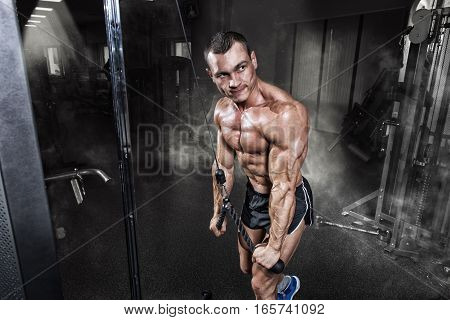 Athlete muscular bodybuilder training on simulator in the gym