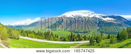 Panorama of the huge mountain range from the green covered with meadows and coniferous forest Samegrelo-Zemo Svaneti Georgia.