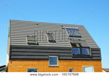 Energy Efficiency New Passive House Building Concept. Closeup of Solar Water Panel Heating Dormers Solar Panels Skylights Ventilation and Air Conditioning Systems Installed