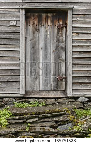 Wooden old rusty cabin door with stone stairway. Visit Norway