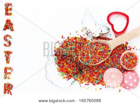Easter baking ingredients - colorful sugar sprinkles cookie cutters paper tins for cake isolated on white background empty space for text top view