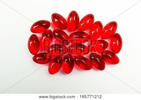 Red capcules with vitamin E on white background. Heap of red pills