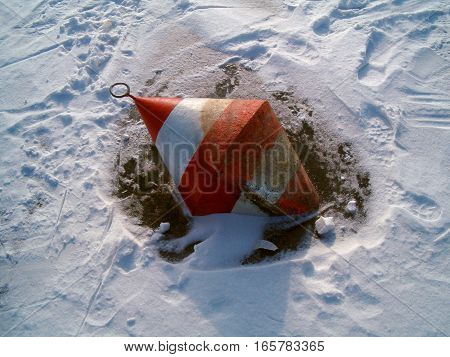 Picture of a red and white buoy frozen in ice