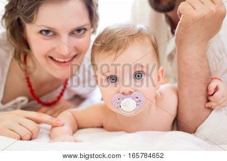 Happy family, mother, father and daughter resting on the white bed