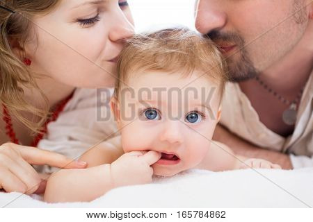 Happy family, mother, father and daughter resting on the white bed