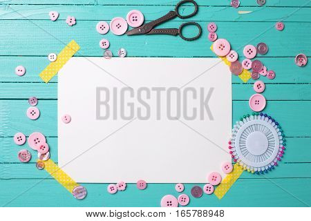 Sewing thread - buttons scissors and empty tag on turquoise wooden background. Selective focus. Scrapbboking. Flat lay. Place for text.