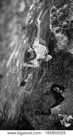 Muscular Rock Climber Climbs On Cliff Wall With Rope