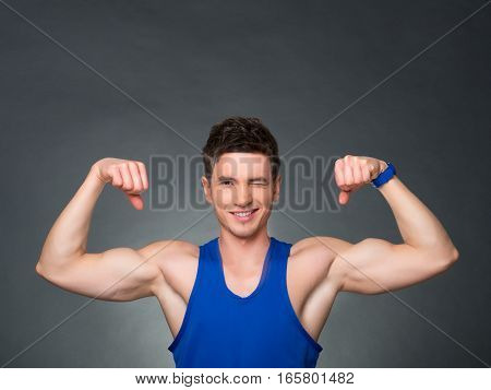 Handsome man showing off his biceps on black background, blue t-shirt
