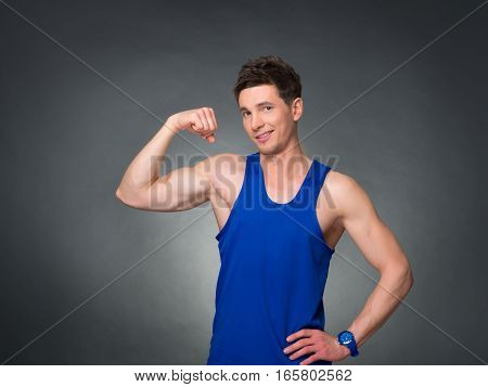 Handsome man showing off bicep on black background, blue t-shirt