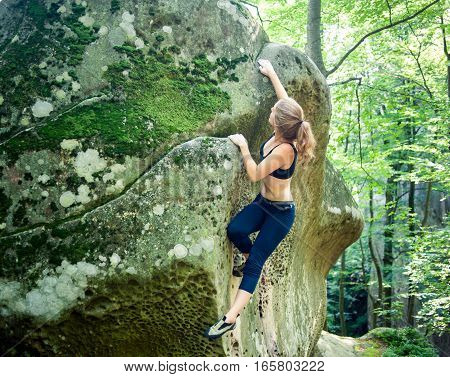 Young Woman Climbing On Large Boulders Outdoor