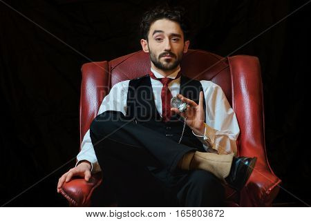 portrait of a young businessman with a pocket watch in a chair.