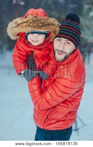 father holding the baby in his arms on the winter background