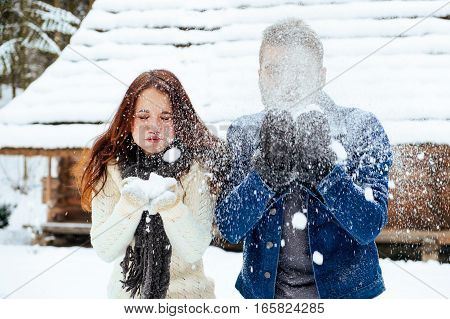 Winter couple having fun playing in snow outdoors. Young joyful happy multi-racial couple