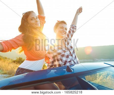 Two young happy girls having fun in the cabriolet outdoors