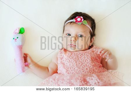 Charming baby. Baby girl playing with toy rattle lying on back