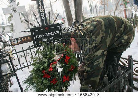 Bucharest Romania December 25 2009: A man lights a candle at the grave of Elena Ceausescu during commemoration of her death. Year after year Romania's nostalgic Communists gather to mourn Ceausescu who was executed on Christmas Day together with his wife