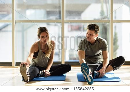 Two People Streching Their Legs In Gym.