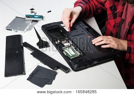 Dismantling laptop computer. Person performing service cleaning and disassembling on an old laptop computer