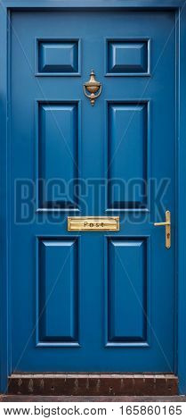 Classical blue door with golden postbox, knocker, knob
