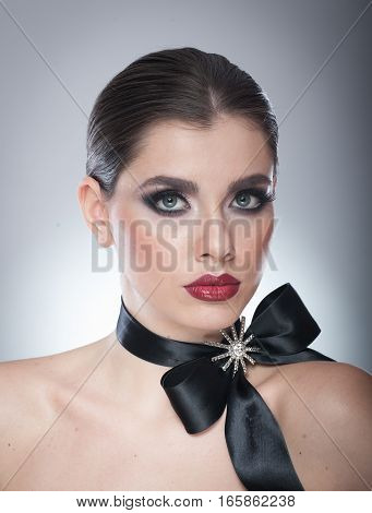 Hairstyle and Make up - beautiful female art portrait with black ribbon. Elegance. Genuine Natural brunette with ribbon - studio shot. Portrait of a attractive woman with beautiful eyes and red lips