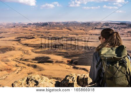 Young woman with backpack enjoying desert landscape in Israel. Tourist traveler on background view mock-up. Active Lifestyle concept.