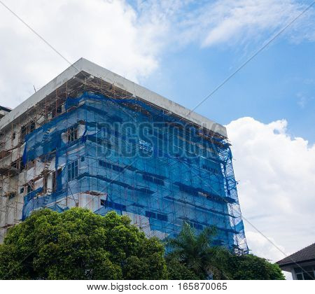 Building construction covered with blue plastic net photo taken in Depok Indonesia java