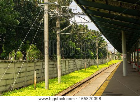 Commuter railway with green bushes view from a station photo taken in Depok Indonesia java