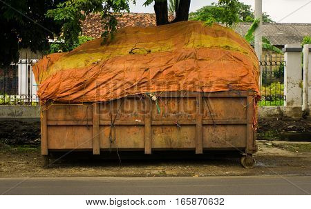 An orange tailgate of garbage truck fullfilled with trashes and covered by plastic photo taken in Jakarta Indonesia java