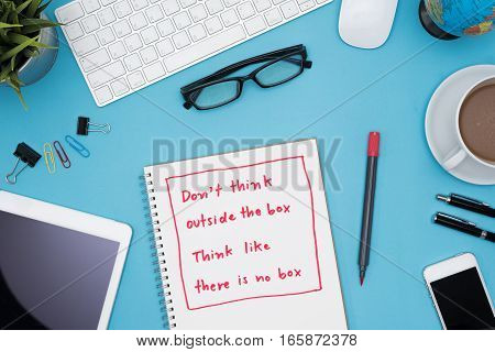 Think different business concept Do not think outside the box think like there is no box on notebook with office supplies over blue desk table background