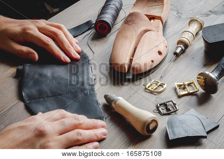 cobbler tools in workshop on dark background close up with hands