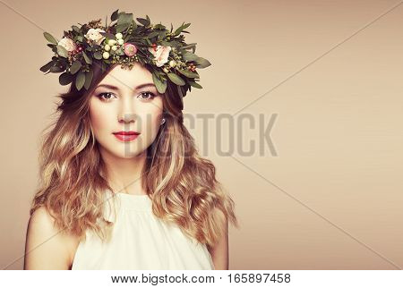 Beautiful blonde woman with flower wreath on her head. Beauty girl with flowers hairstyle. Perfect makeup. Beauty fashion. Spring woman
