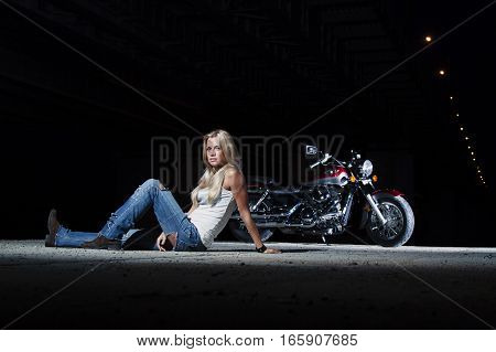 Young sexy blonde is sitting near her motorcycle
