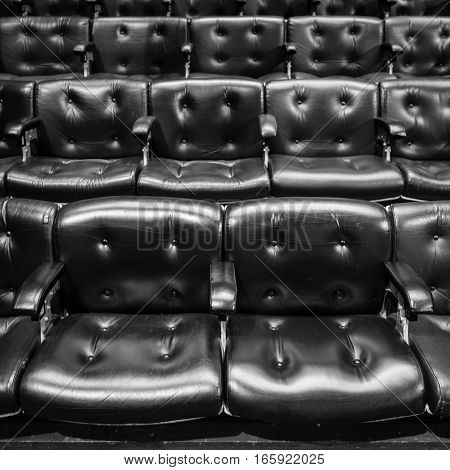 Full frame detail from rows of raked leather seating of the type found in conference or concert halls.