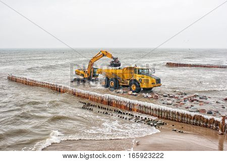 excavator loading a truck stones on the beachon cold winter day