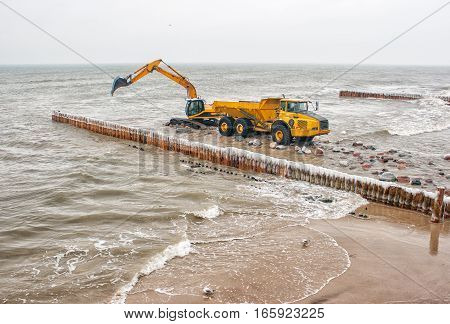 excavator loading a truck stones on the beachon cold winter day