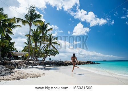 Young pretty woman with beautiful body in swimsuit running in ocean water sunny day at tropicl beach wellness concept