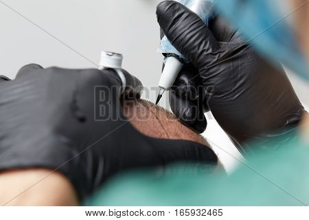 Cosmetologist making permanent makeup on male head - tricopigmentation