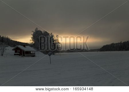 wooden house in snow valley on sunset background in Levi, Finland