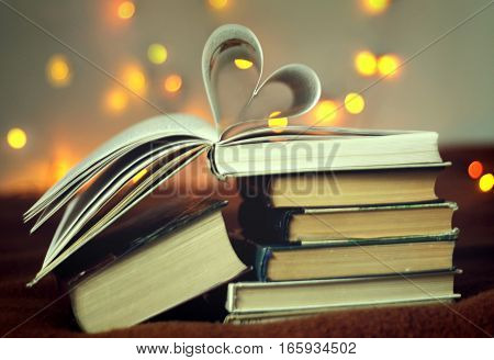 Opened book with heart shaped pages with lights glowing background, concept valentine's day