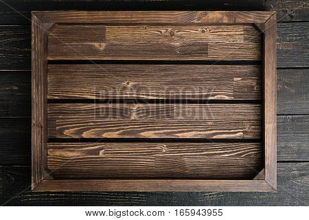 Empty brown wood serving tray on the black wooden table copy space