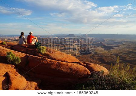 Two hikers enjoy the view form the Green River Overview, looking down into the valley carved by the Colorado and Green River. Canyonlands National Park, Utah, USA