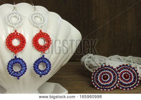 Earrings on white ceramic shell on wooden background