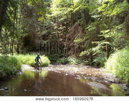 Picture of a cyclist riding through a shallow creek