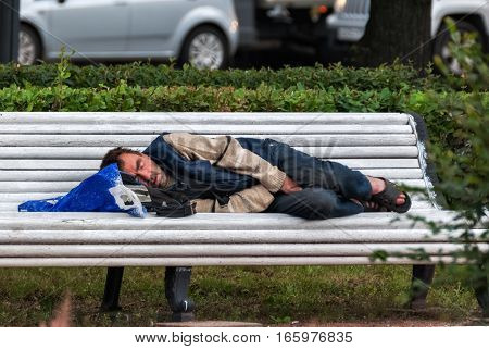 SAINT PETERSBURG RUSSIA may 15: A homeless man sleeping on a bench in the town square in the morning may 15 2016.