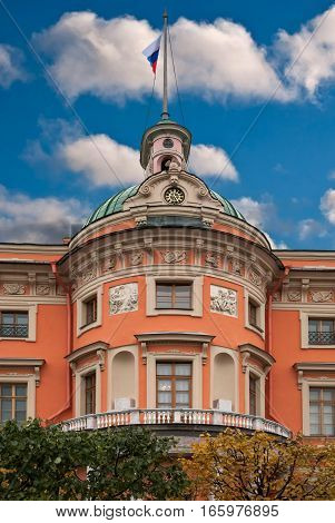 Fragment of the Mikhailovsky castle in Saint-Petersburg with a tower spire and the Russian flag on blue sky background.