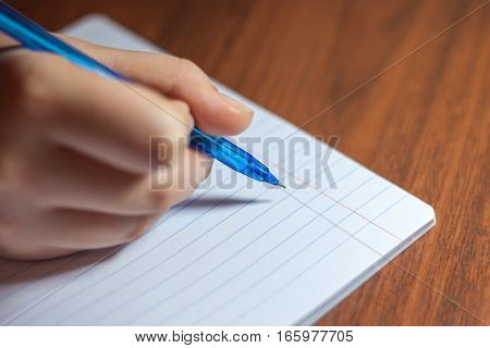 A close photo of a persons writing a letter with a pen.