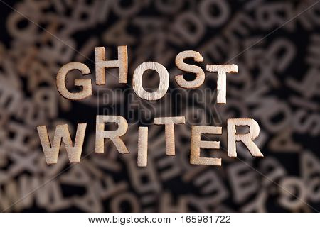 Ghostwriter text in wooden letters floating above random letters out of focus