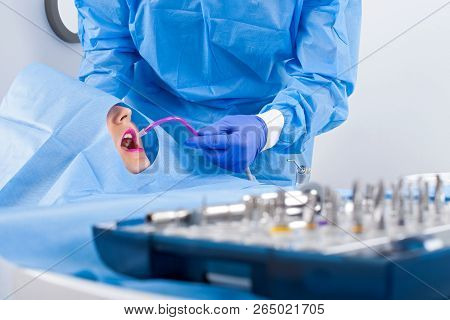 Dentist In Blue Uniform Performing Dental Implant Surgery
